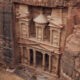 Scenic view of Petra in Jordan, featuring the iconic Treasury carved into rose-red sandstone cliffs, surrounded by rugged desert landscapes